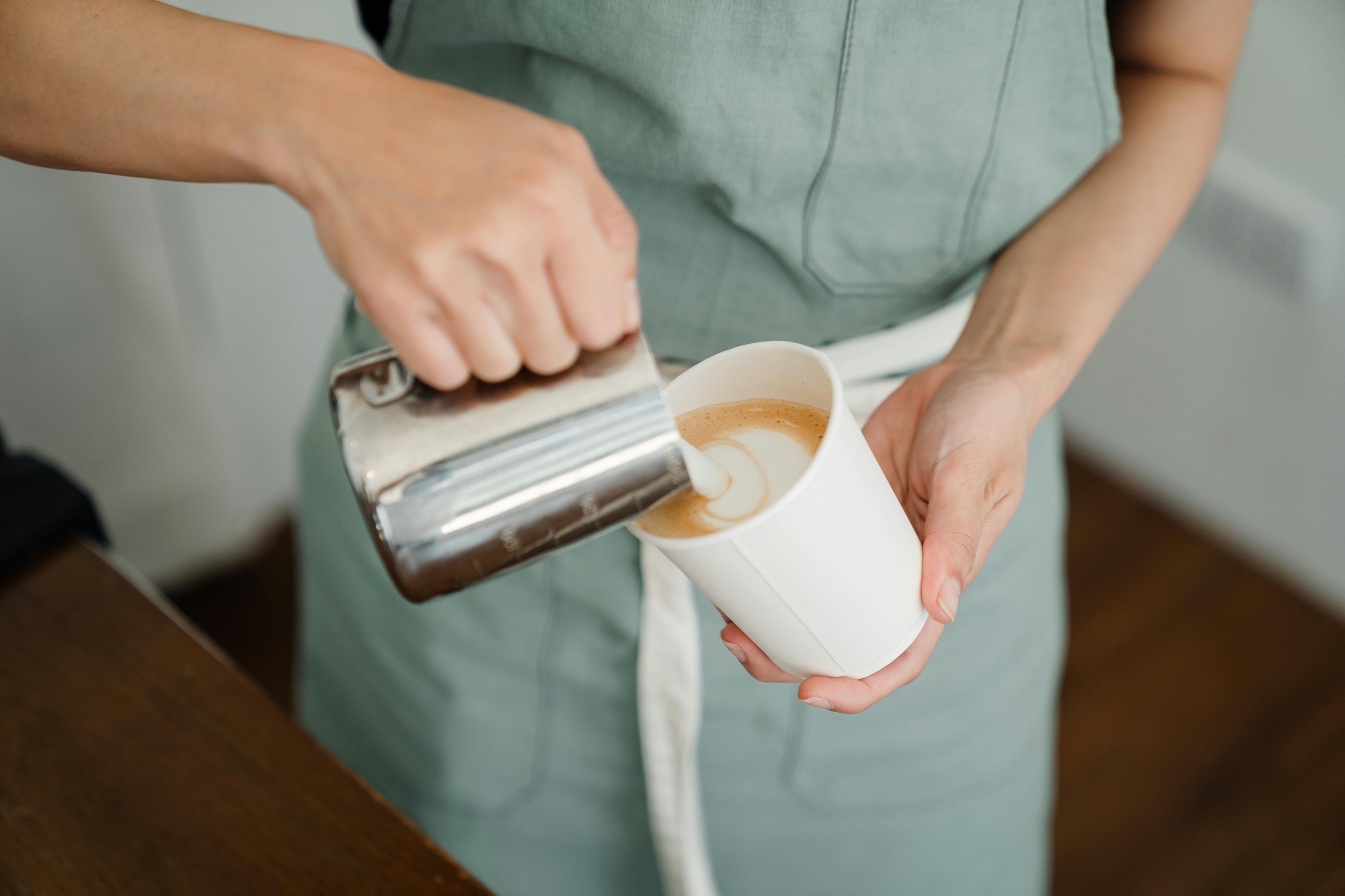 Barista pouring steamed milk into a cup at Cafeina